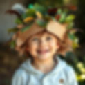 A fun and happy photography of a young child who is wearing an eco-hat that they have made