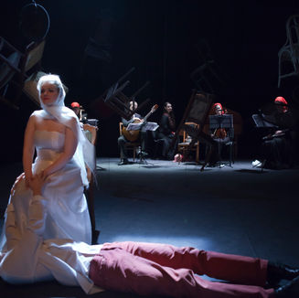 Scene from 'No Pictures Expected' musical by Diana Stein: Mysterious character is sitting next to a man lying on the floor.
