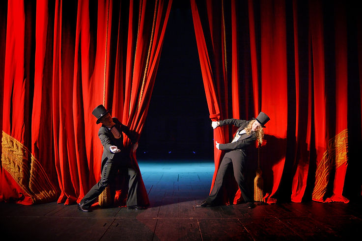 Actor and actress in tuxedos open theater curtain.jpg