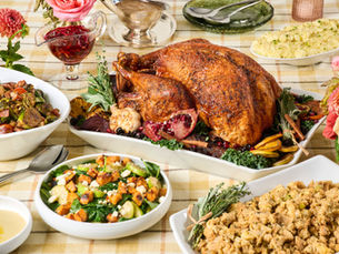 Full Thanksgiving spread featuring whole roasted turkey, salad, brussels, stuffing, cranberry relish, and gravy on a yellow plaid tablecloth