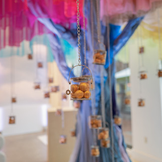 Little tins of macaroons hanging from a colorful tulle tree