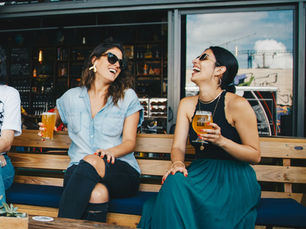 two smiling expat friends enjoying a drink together after relocating abroad