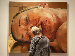 large female portrait painting with woman standing in front of it in museum
