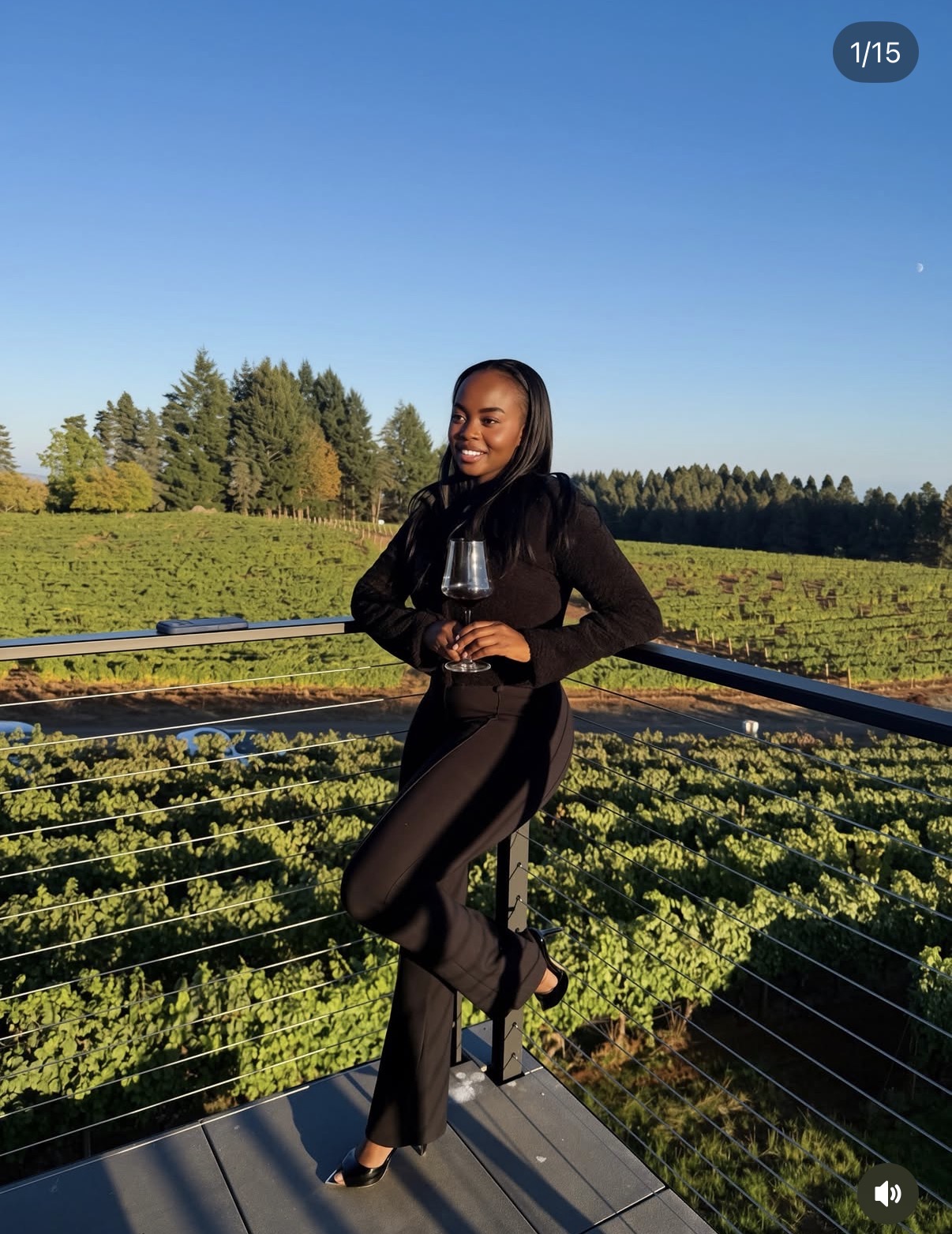 Hadassah in a black outfit holding a glass of wine overlooking a vineyard