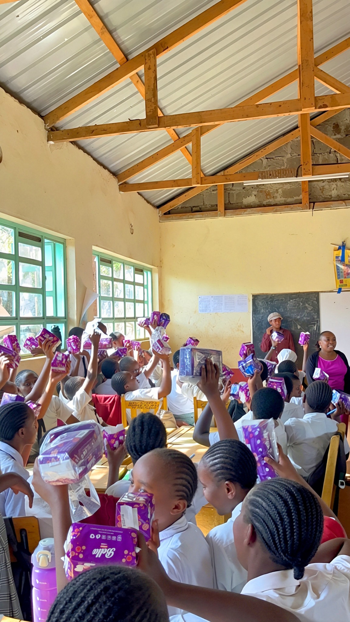 Students holding up packs of sanitary pads during the school visit