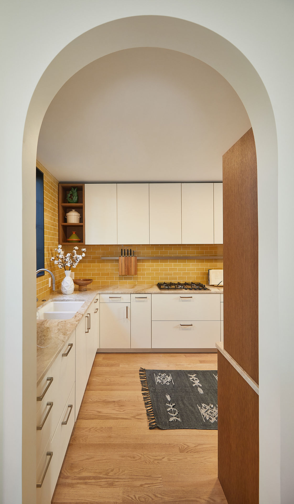 Modern kitchen viewed through arched doorway, yellow tile backsplash. LEICHT German cabinetry by Lifestyle Kitchen Studio