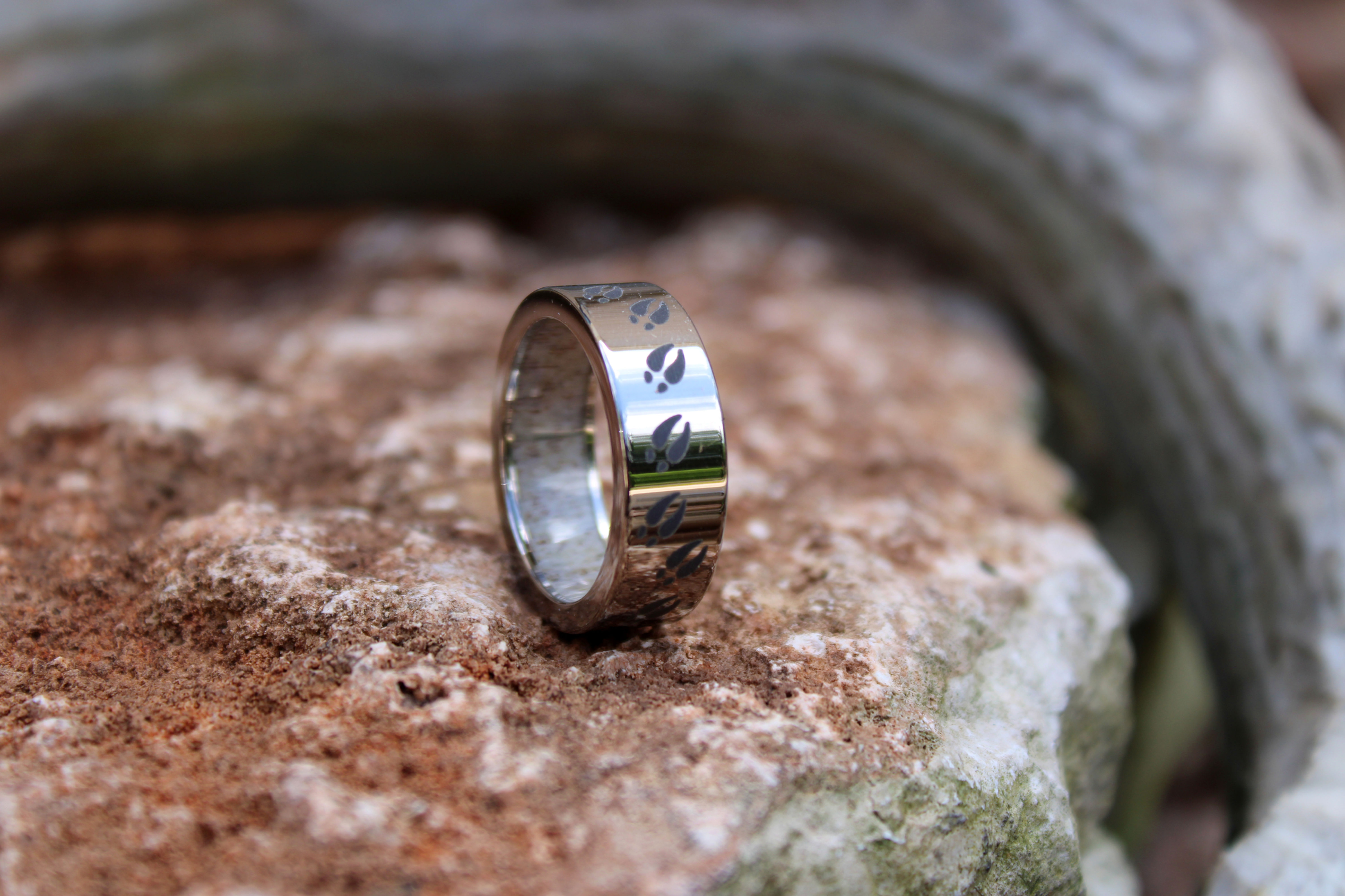 Shiny silver-colored ring with dark hoofprint motifs