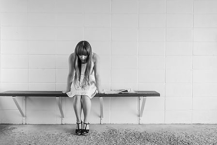 A teenage girl looking down sitting on a bench