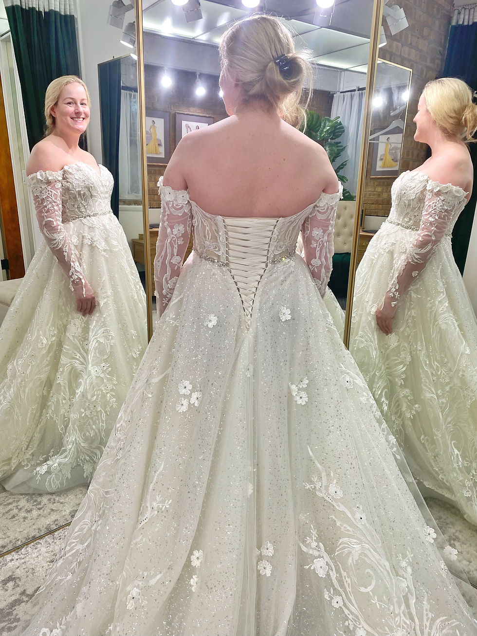 A happy bride smiling in a mirror during a fitting at Agadesal, wearing a wedding gown with a professionally finished custom lace-up corset back.