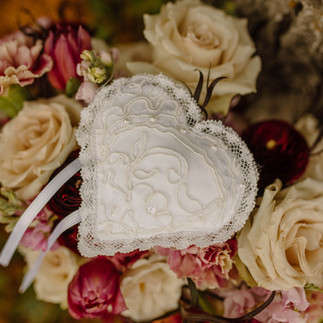 white lace heart pillow on top of florals