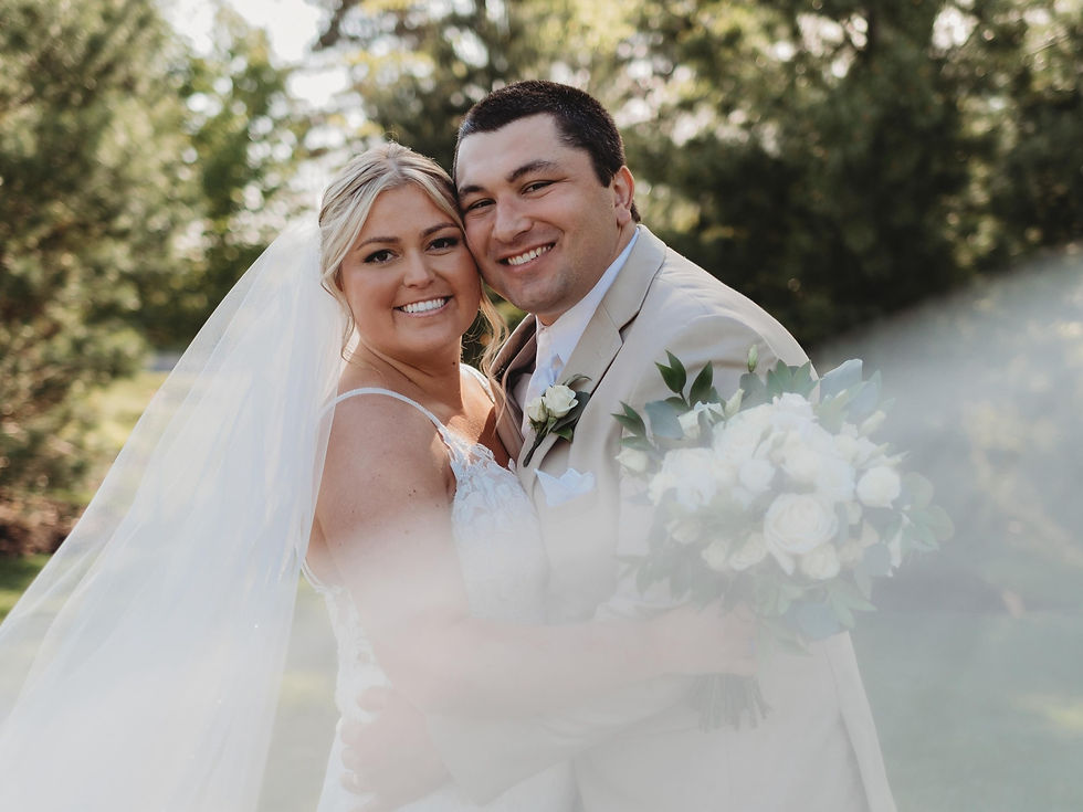 smiling bride & groom hugging and looking at camera