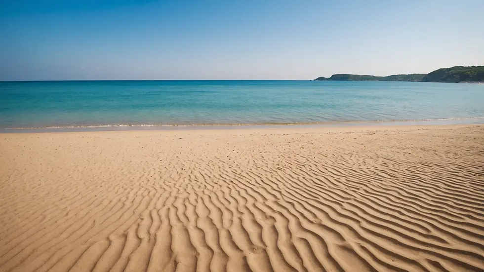 Wide angle view of a sandy beach with clear blue water