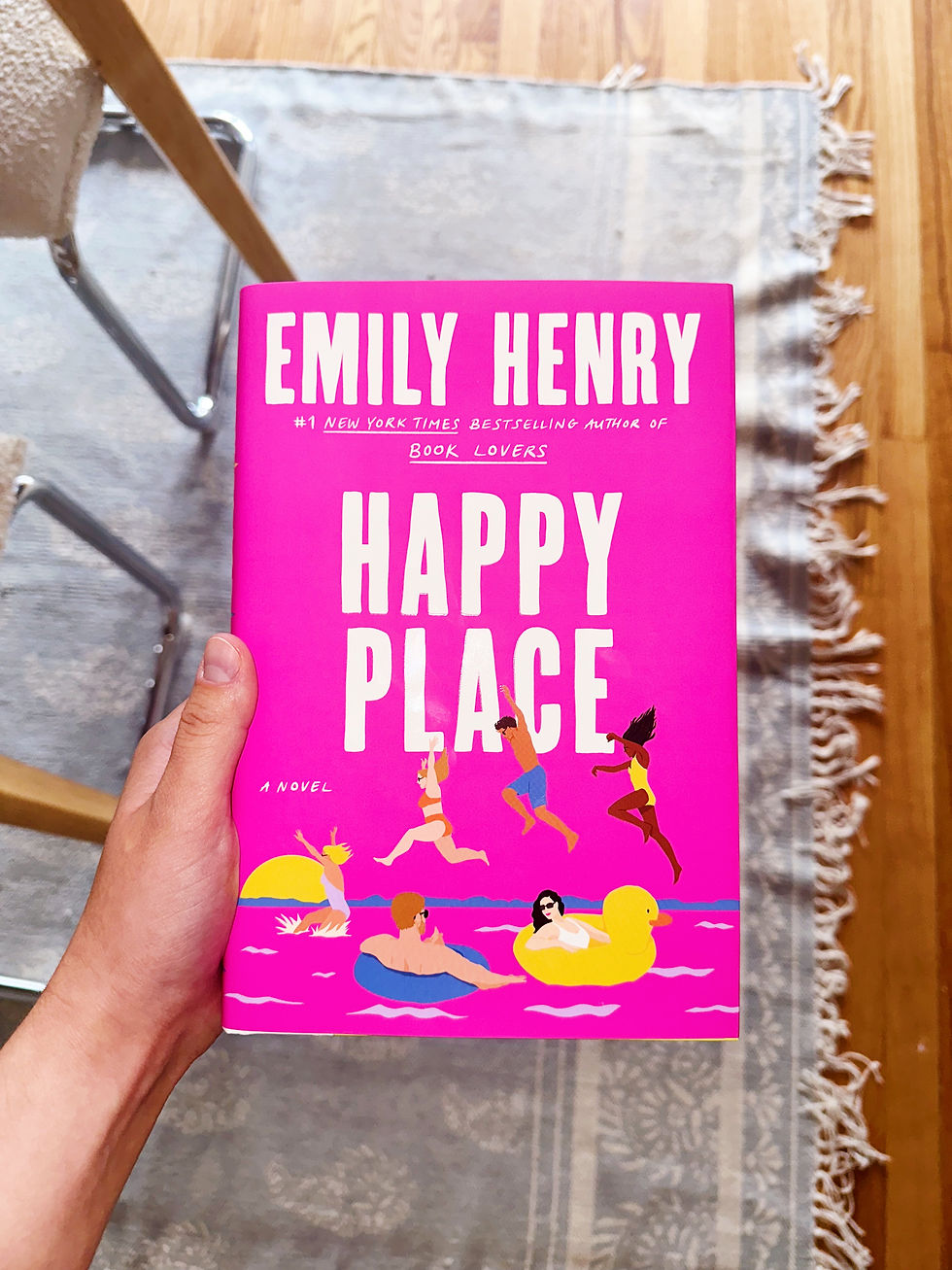 tiffany holding a hard cover of "Happy Place" by Emily Henry