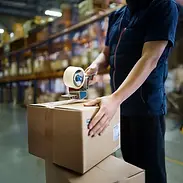 Warehouse team member sealing a carton for kitting, assembly, and fulfillment operations