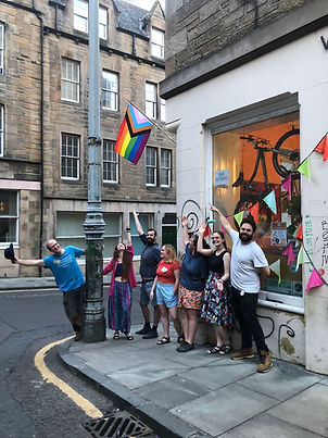 Photo of our volunteers and staff in front of our workshop decorated with pride flag and bunting for the our reopenning