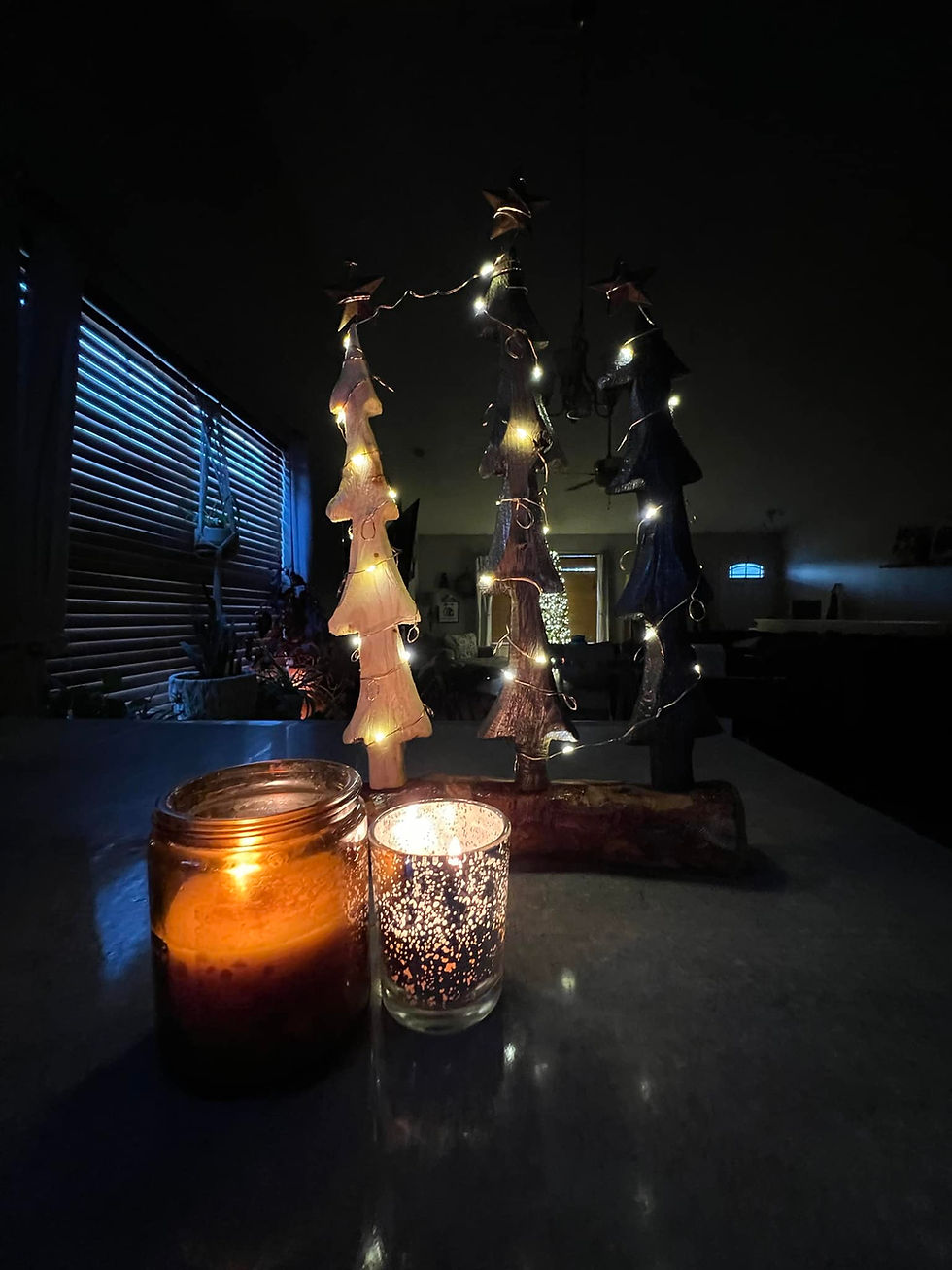 Lit candles beside illuminated Christmas trees