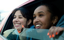 Multiple overlapping reflections of a person with curly hair and a floral headpiece, shown in soft layered imagery.