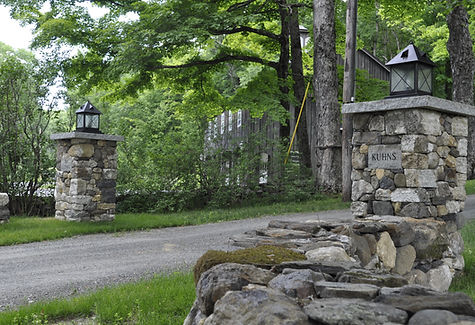 A native fieldstone wall and pillars flank a driveway entrance in Ashfield, MA