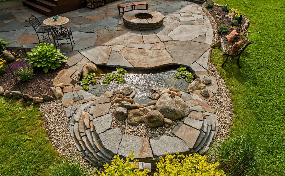 A Sugarledge Stone flagstone patio with stone fire pit, wall, and water feature in Ashfield MA 