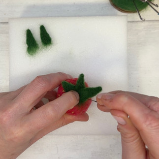 the green triangular leaves are added to the top of the strawberry