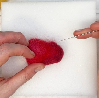 A darker blend of red and elderberry wool fibres is felted to the bottom of the strawberry.