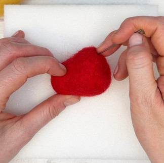 Repeat to add another little patch of red wool in the same way and then keep felting small patches until your core is covered.