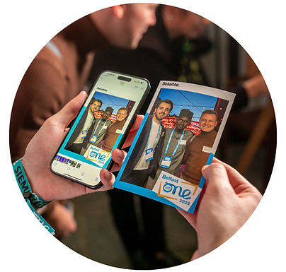 da40d5 5b99fe8ea558494d84fc9d71bbd5415b~mv2 Close-up of a person holding a smartphone and printed photo side by side, showing a ProptographyCo branded corporate event photo booth experience.