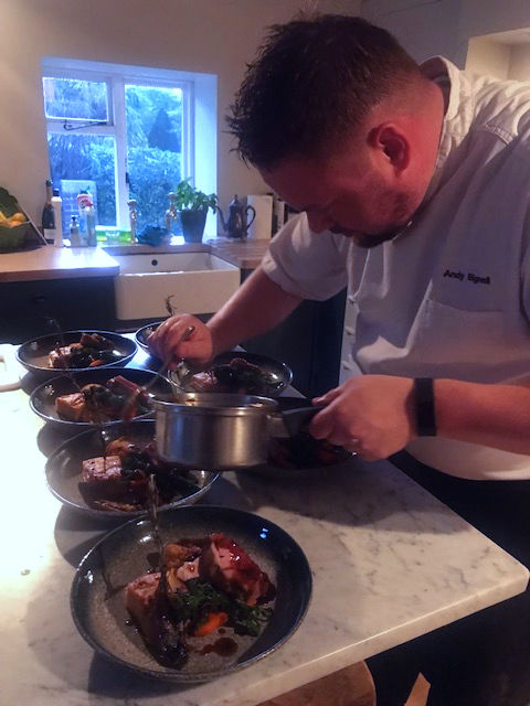Eye-level view of a private chef plating a gourmet dish in a modern kitchen