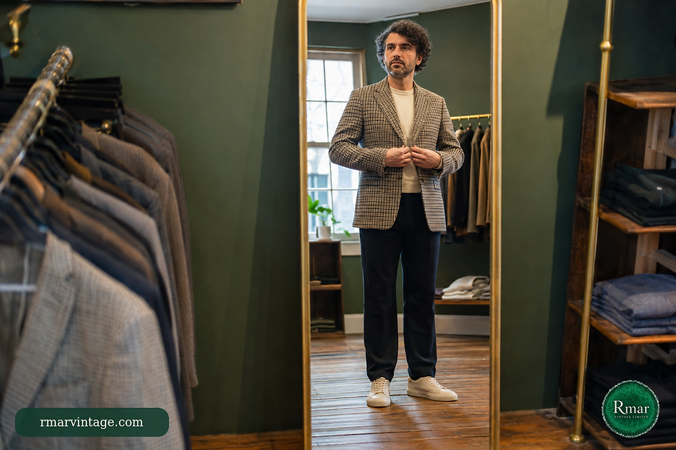 Customer styling a checked vintage jacket with a cream top and modern dark trousers in a full-length mirror.