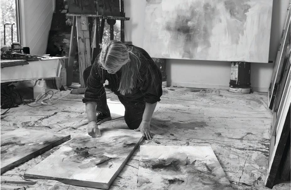 Kathy Buist hunched over paintings in her studio in East Hampton. Photo by Ben Flythe