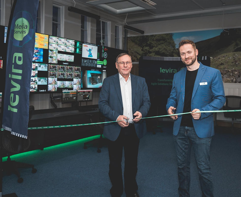 Two men in suits cut a ribbon in a tech control room. Multiple screens display images. "Levira" and "Media Services" logos are visible.