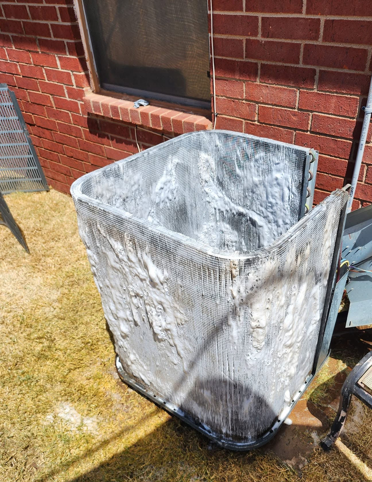 Residential outdoor HVAC condenser being cleaned and maintained