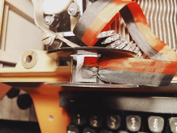 The inside of a typewriter ribbon showing the barb connecting with the ribbon end.