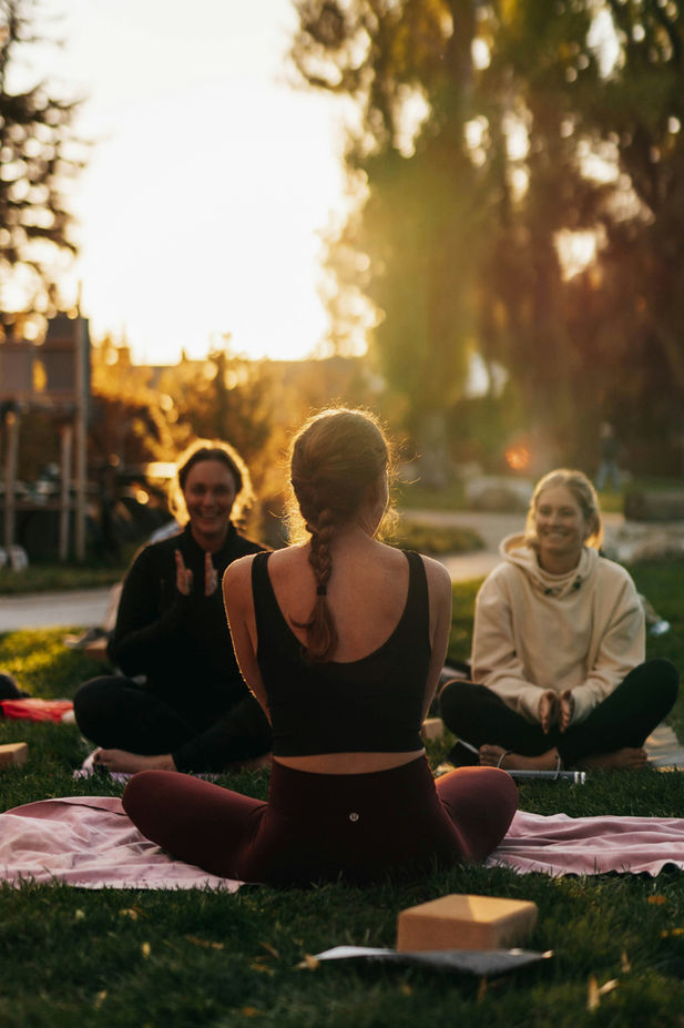 Séance de yoga en plein air avec 3 femmes au coucher du soleil.