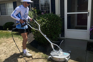 Man using a surface cleaner to clean pavers and sidewalks on a residential home