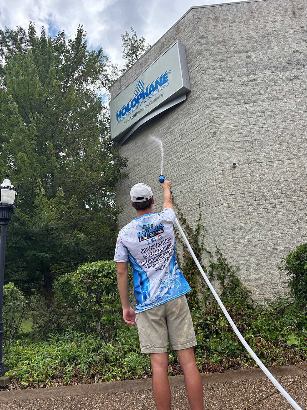 Eye-level view of a commercial building exterior being cleaned with a soft washing system