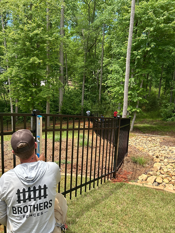 Brothers Fences employee installing black aluminum fence.