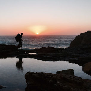 Hiking toward a stunning sunset over the ocean