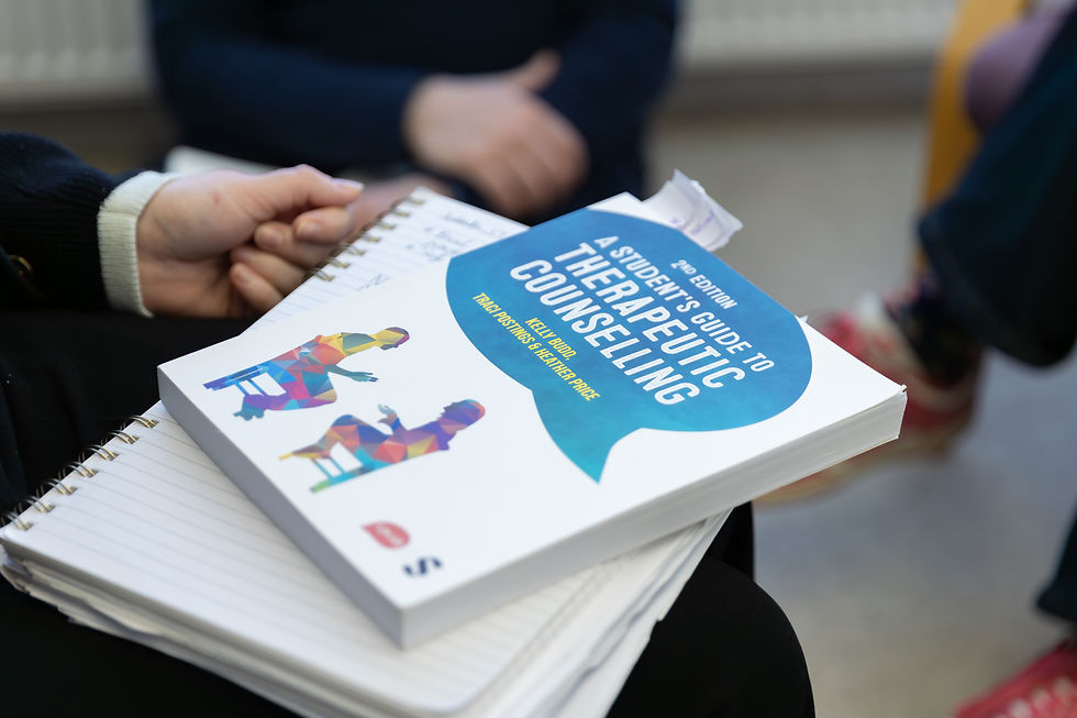 Pictyre of a students notebook with a copy of the CPCAB's Therapeutic Counselling Textbook on top