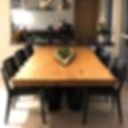 Mesa de jantar em madeira maciça com pés em aço carbono, acompanhada de cadeiras de madeira na cor preta