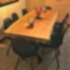 Mesa de jantar em madeira maciça com pés em aço carbono, acompanhada de cadeiras de pretas