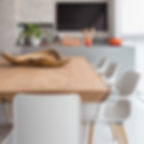 Mesa de jantar em madeira maciça com pés em acrílico, acompanhada de cadeiras brancas