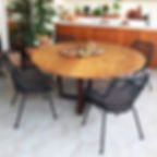 Mesa de jantar redonda em madeira maciça, acompanhada de cadeiras tramadas pretas