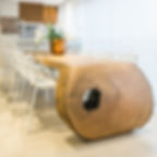 Mesa de jantar em madeira maciça curva, acompanhada de cadeiras de brancas