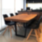 Mesa de jantar em madeira maciça com pés em aço carbono, acompanhada de cadeiras de pretas