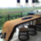 Mesa de jantar em madeira maciça curva, acompanhada de cadeiras e puffs em corda