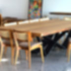 Mesa de jantar em madeira maciça com pés em aço carbono, acompanhada de cadeiras de madeira