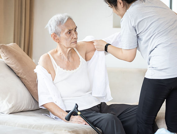 Asian female caregiver taking care of helping elderly patient get dressed,wearing clothes 