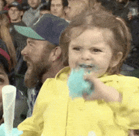 a little girl, holding blue cotton candy, is making extremely excited faces