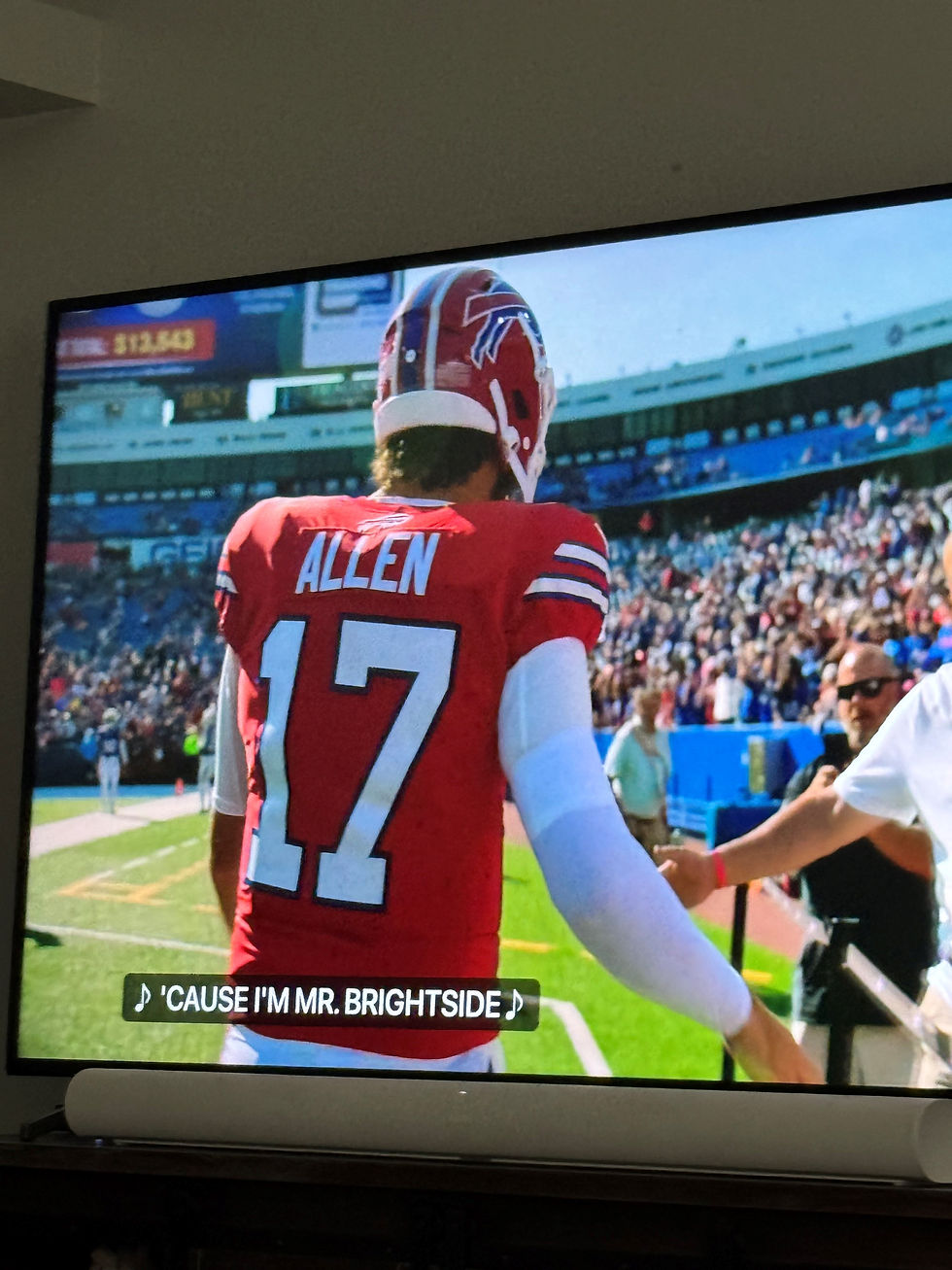 a football player in a red jersey and red helmet is clapping fans hands as he walks around the stadium